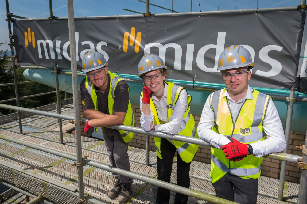 Three trainees in hi-visibility jackets on a Midas building site.