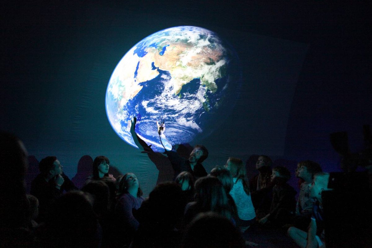 A man points at an image of the earth in side the dome