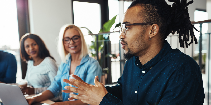 A Black man with glasses and dreads leading a group discussion