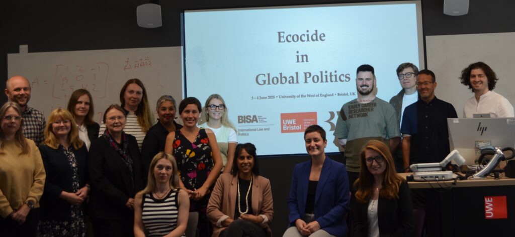Group photo of workshop participants in front of a slide titled "Ecocide in Global Politics"