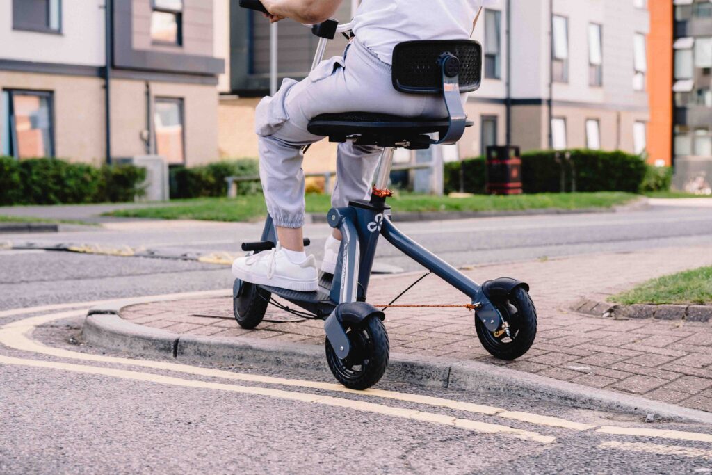 a Supersmith 3scooter navigating a tight space, one wheel is off the curb while the other two remain on the pavement 