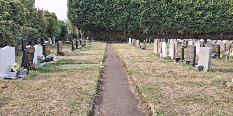 A picture of a path in a graveyard with graves either side